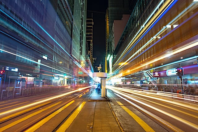 City street with light trails and skyscrapers, illustrating 5G connectivity in urban areas.