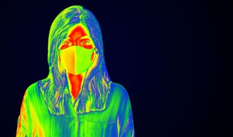 Thermal imaging of a woman wearing a mask to illustrate visual technologies for health monitoring.