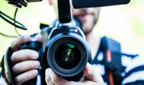 Photographer holding a professional camera ready to shoot, emphasizing the importance of photos in v.