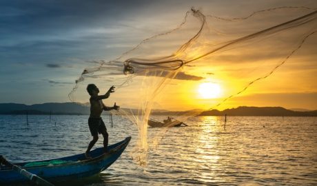 Fishing at sunset on a boat with a net in the water.