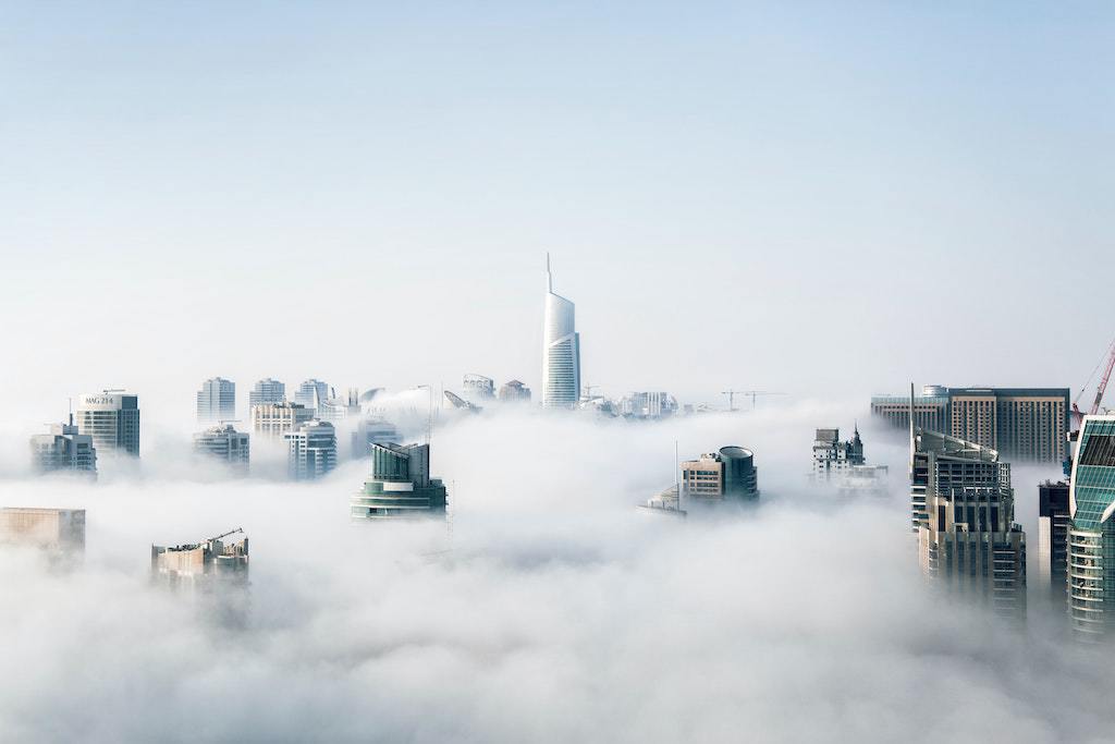 Aerial view of a modern city skyline with skyscrapers emerging through fog.