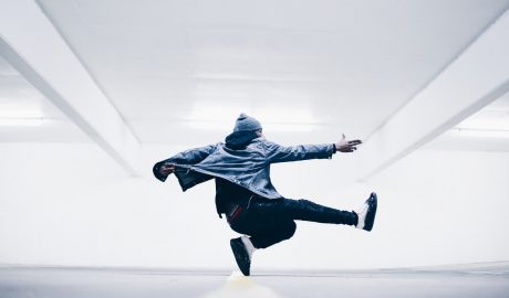 An energetic dancer performing a dynamic move in a modern, minimalistic setting.