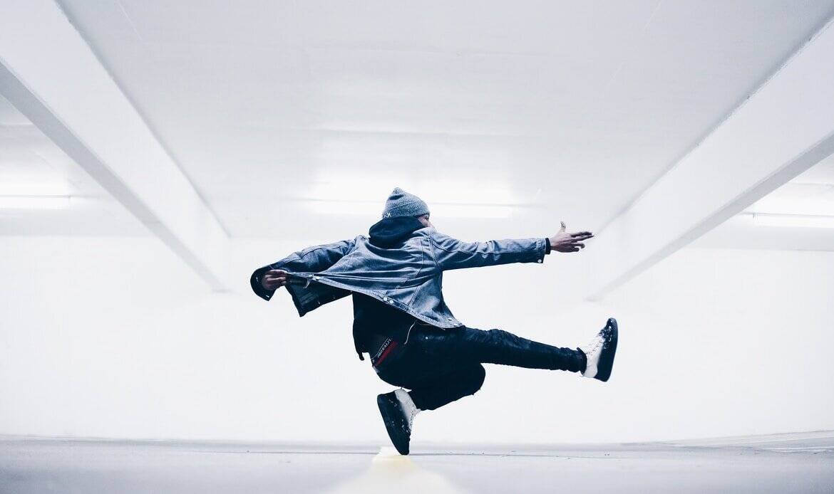 An energetic dancer performing a dynamic move in a modern, minimalistic setting.