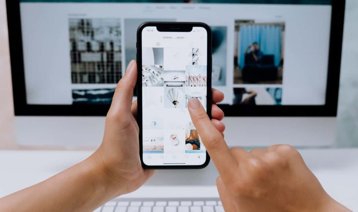 a cell phone in front of a computer screen, both with photos on their screens