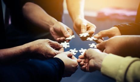 hands holding puzzle pieces in a circle