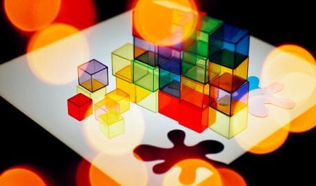 Colorful transparent cubes stacked on a white surface with bokeh lighting effects.