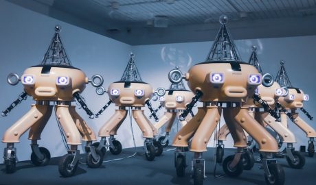 Group of AI-powered robots with multiple legs and cameras at a tech event.