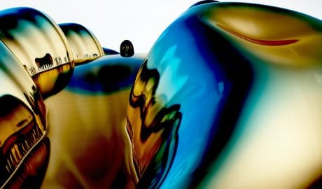 Reflective metallic sculptures with vibrant colors and smooth surfaces.