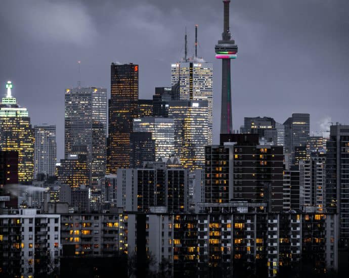 Night view of Toronto skyline with illuminated buildings and CN Tower.