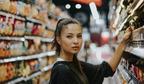 Young woman shopping for snacks in a grocery store aisle.